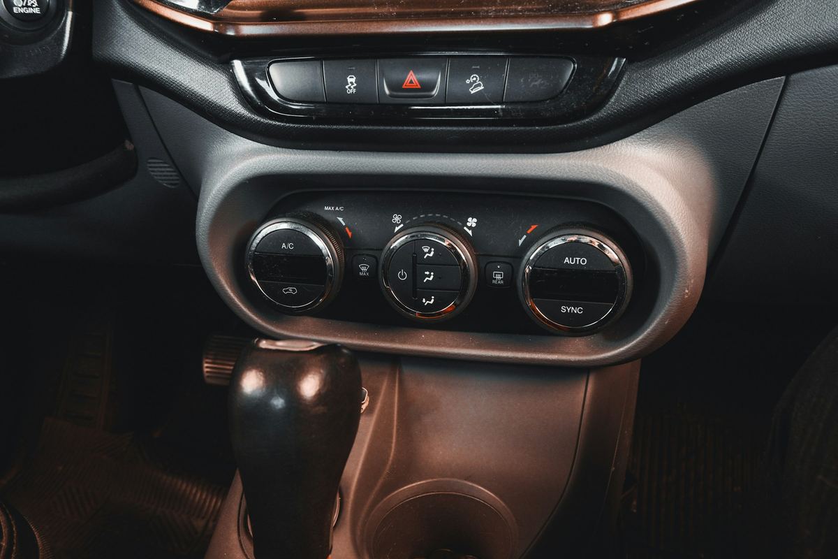 Het dashboard van een wagen met airco-knoppen en een automatische versnellingspook